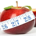 una mela rossa in primo piano con un centimetro che la misura in diagonale, l'immagine rappresenta il corso di consulente ed educatore alimentare