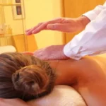 una donna sdraiata su un lettino per massaggi e un kinesiologo che svolge la terapia, l'immagine rappresenta il corso di kinesiologia