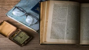 una scrivania con un libro aperto e degli occhiali da lettura e altri oggetti che rappresentano il corso di operatore di biblioteca