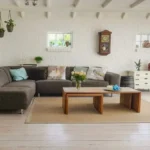 un salotto di una casa con colori chiari e un divano grigio con un tavolino in legno, l'immagine rappresenta il corso di home therapy e design