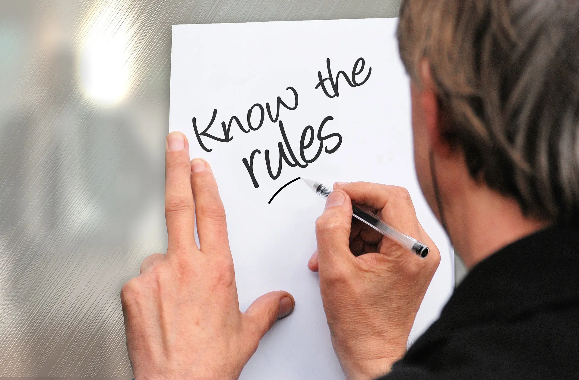 un uomo scrive su un foglio know the rules